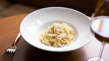 A white bowl of pasta with grated cheese on a wooden table.