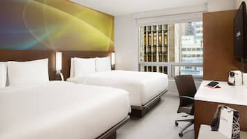 A hotel room with two beds, a desk, a chair, and a large window with a city view.