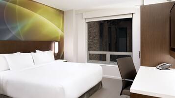 Une chambre d’hôtel avec un grand lit, un bureau et une fenêtre donnant sur un mur de briques.