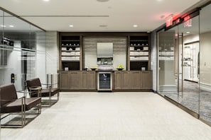 En moderne hotellobby med et siddeområde, minibar og en glasvæg med udsigt.