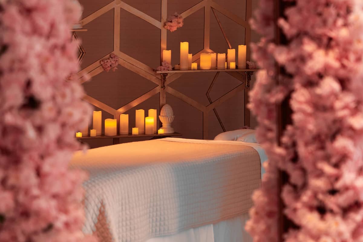 Ein Schlafzimmer mit einem Bett, mehreren Kerzen auf Regalen und einem geometrischen Wandmuster.