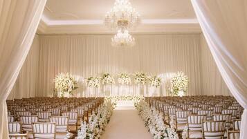 An aisle with rows of chairs and a floral arrangement at the end.