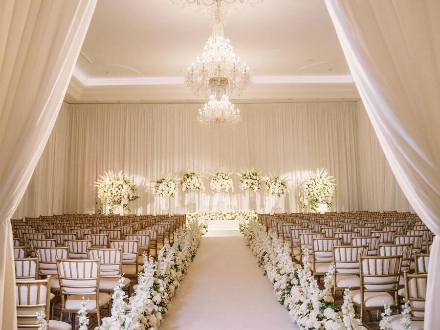 An aisle with rows of chairs and a floral arrangement at the end.