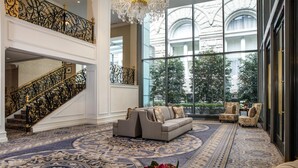 A grand lobby with a high ceiling, ornate black iron railings, a large patterned carpet, and a seating area with sofas and armchairs. - Waldorf Astoria Washington DC (Washington)