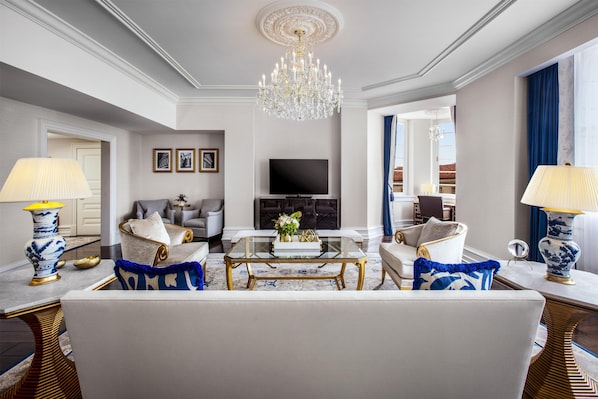 Amplia sala de estar con candelabro, televisor de pantalla plana y chimenea. Hay dos sofás, una mesa de centro y lámparas decorativas.
