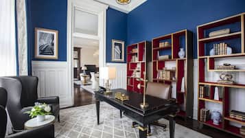 Una habitación con una mesa negra, estanterías rojas, una silla blanca y un cuadro en la pared.