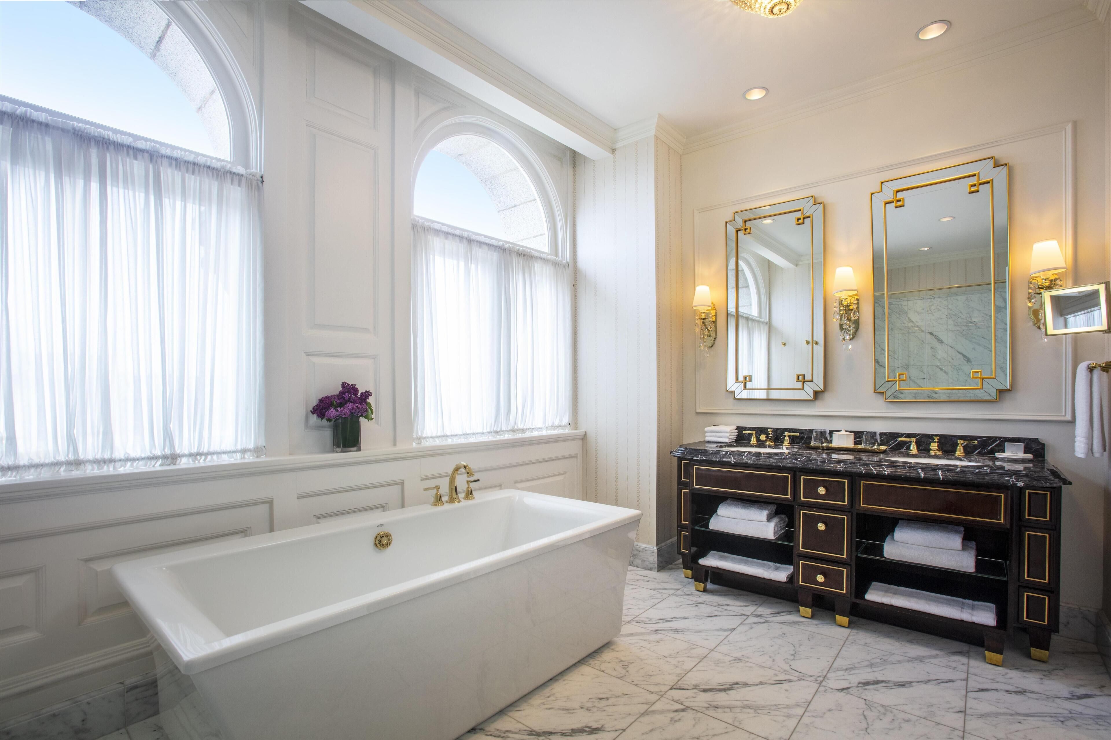 A luxurious bathroom with a large bathtub, double sinks, and a marble floor.