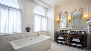 A luxurious bathroom with a large bathtub, double sinks, and a marble floor.