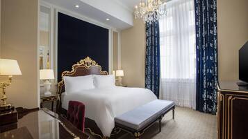 Una habitación de hotel con una cama grande, un escritorio, una banca y un candelabro.