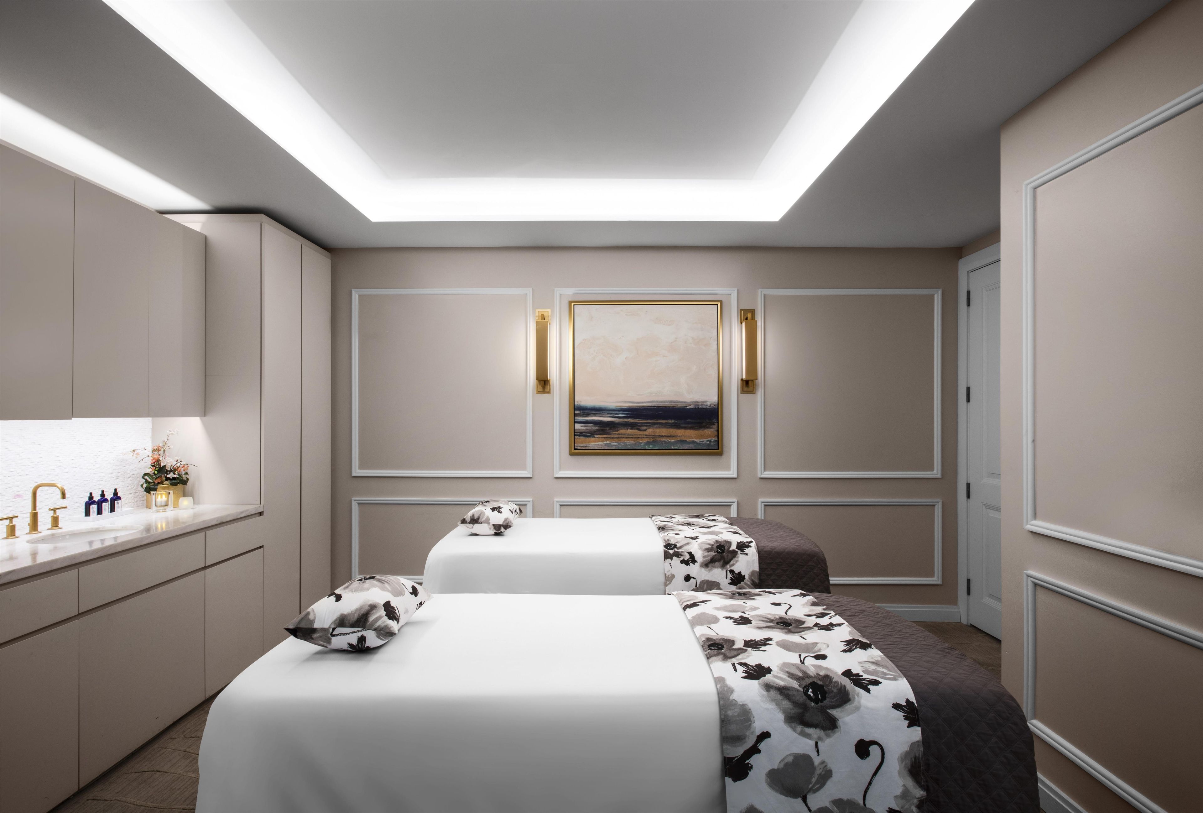 A modern hotel room with a skylight, a large painting, and a neatly arranged bed with a floral bedspread.