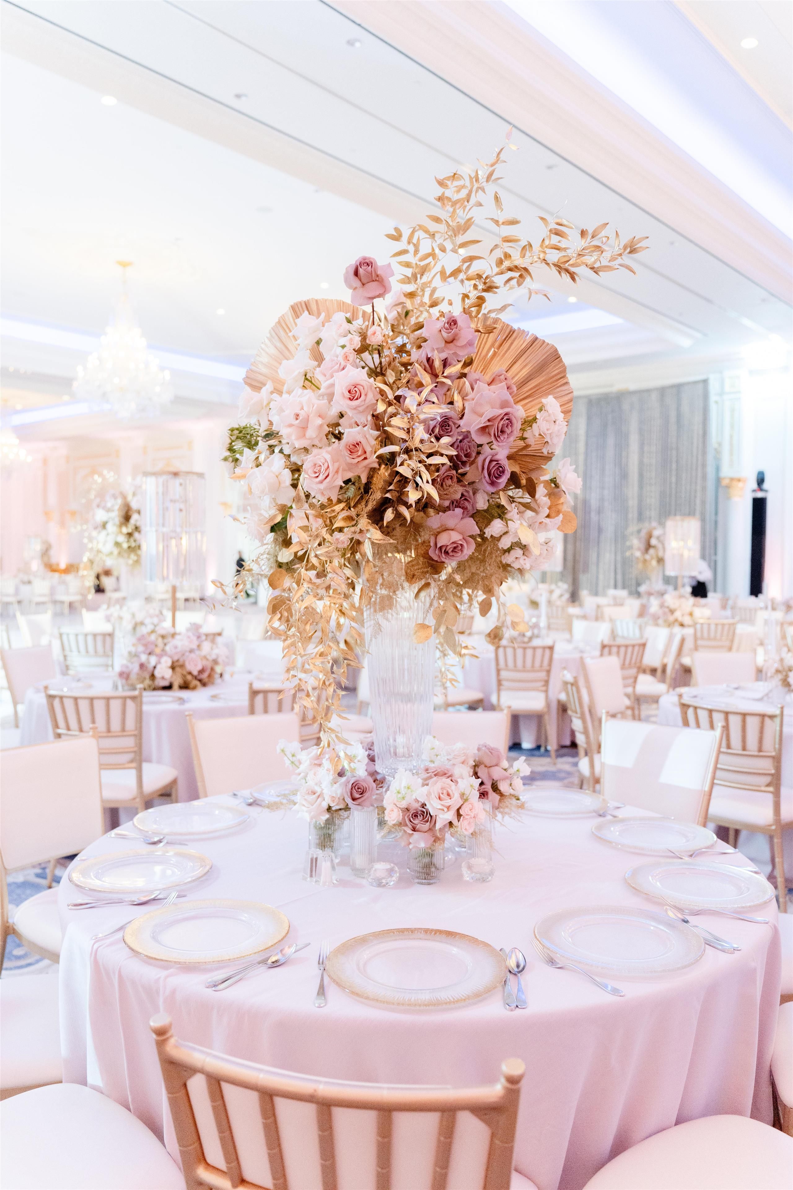 A banquet hall with round tables set for a formal event, featuring floral centerpieces and elegant table settings.