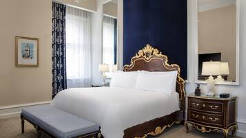 Uma cama grande com cabeceira de madeira, uma mesa de cabeceira com luminárias e um banco.