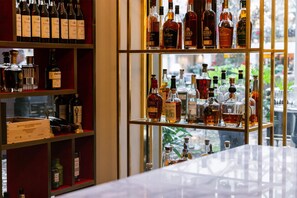 A bar area with shelves of liquor bottles and a view of greenery outside.