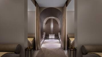 A modern hotel corridor with a central arched doorway, two side beds, and a marble floor.