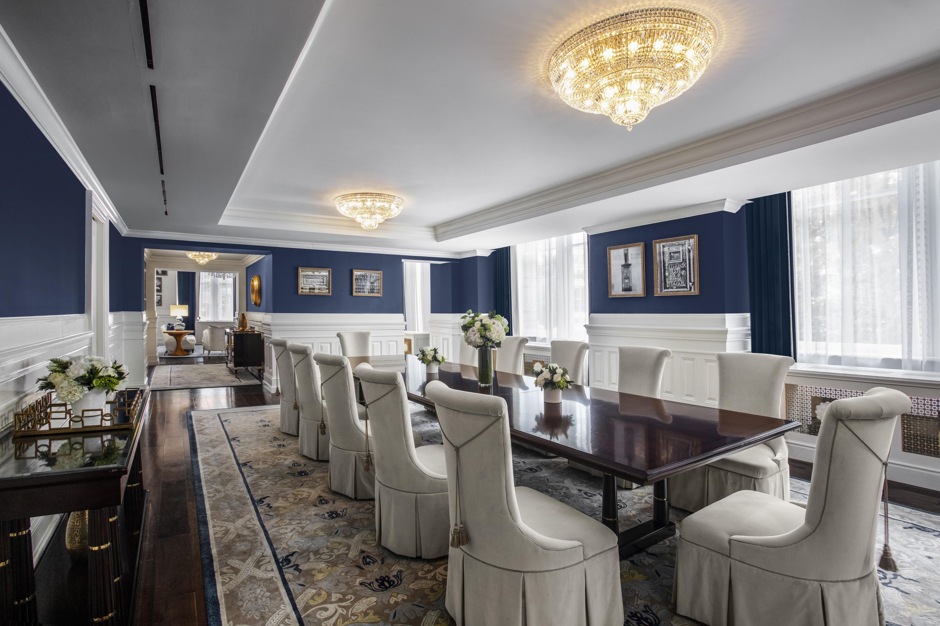 Un comedor formal con una larga mesa, sillas blancas tapizadas y candelabros.