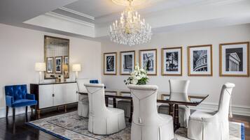 A formal dining room with a chandelier, framed artwork, and a blue armchair.