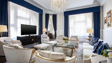 A luxurious living room with a large chandelier, a flat-screen TV, and elegant furniture.