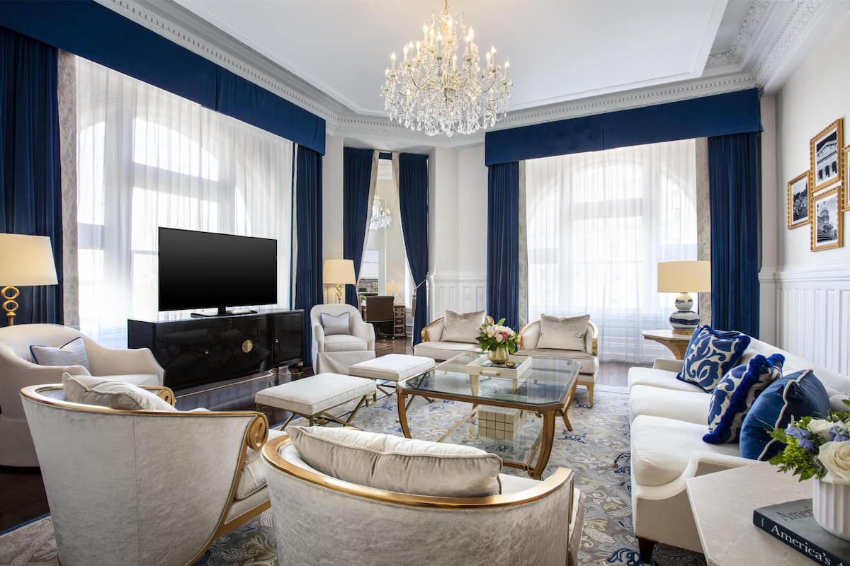 Ein luxuriöses Wohnzimmer mit einer großen Kronleuchter, einem Flachbildfernseher und stilvollem Mobiliar.