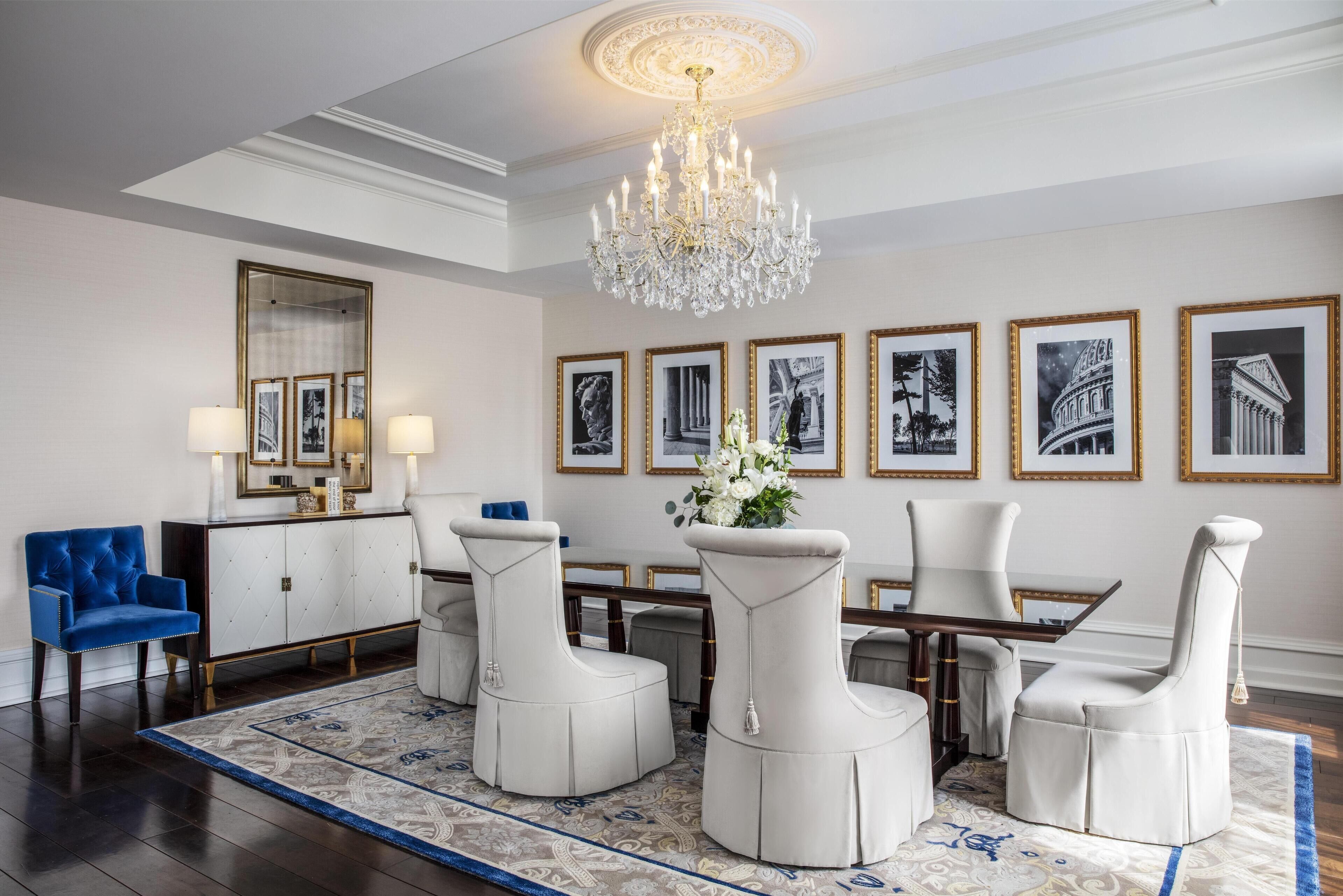 Un comedor formal con candelabro, obras de arte enmarcadas y un sillón azul.
