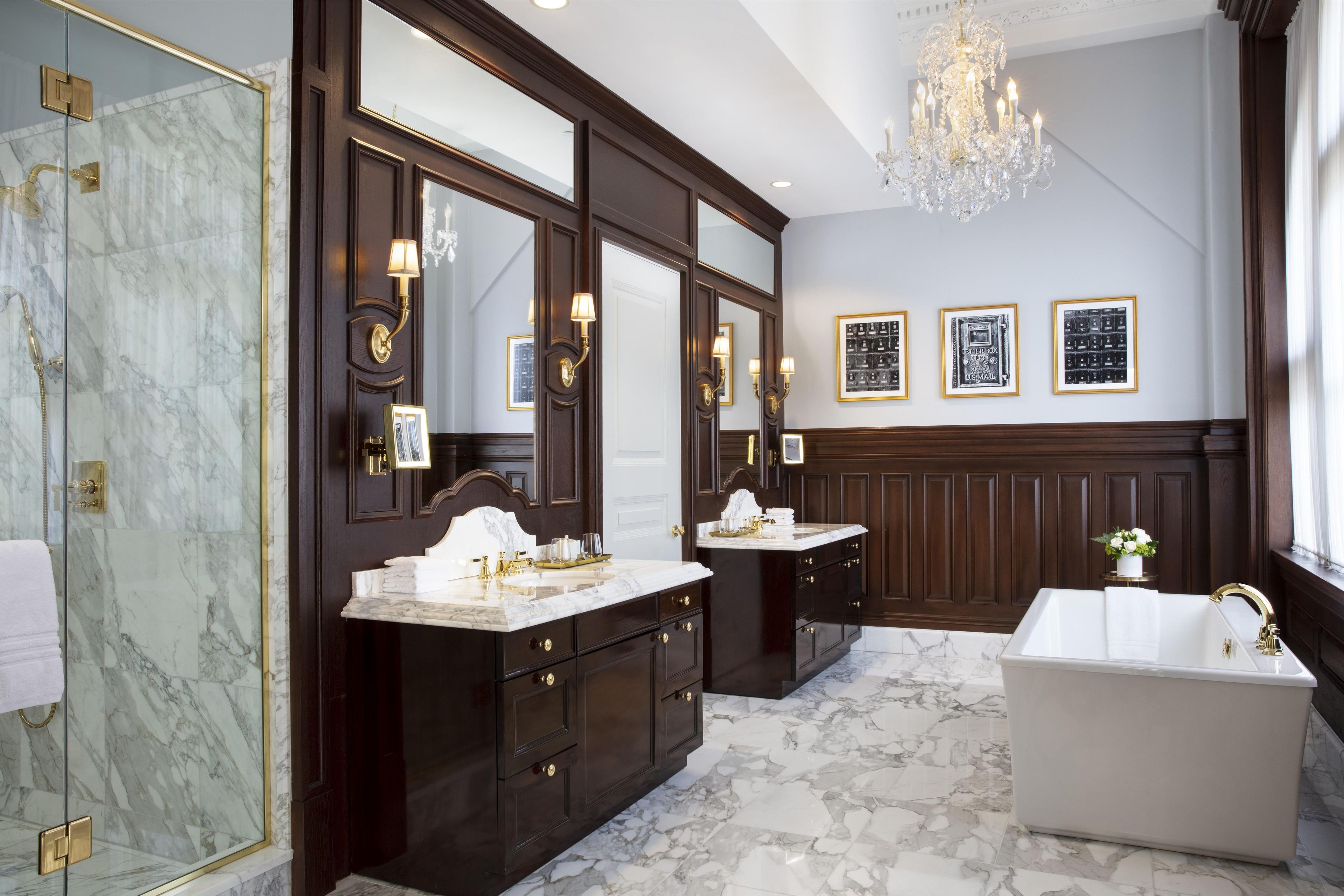 A luxurious bathroom with marble flooring, a freestanding bathtub, and dark wood cabinetry.