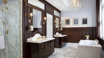 A luxurious bathroom with marble flooring, a freestanding bathtub, and dark wood cabinetry.