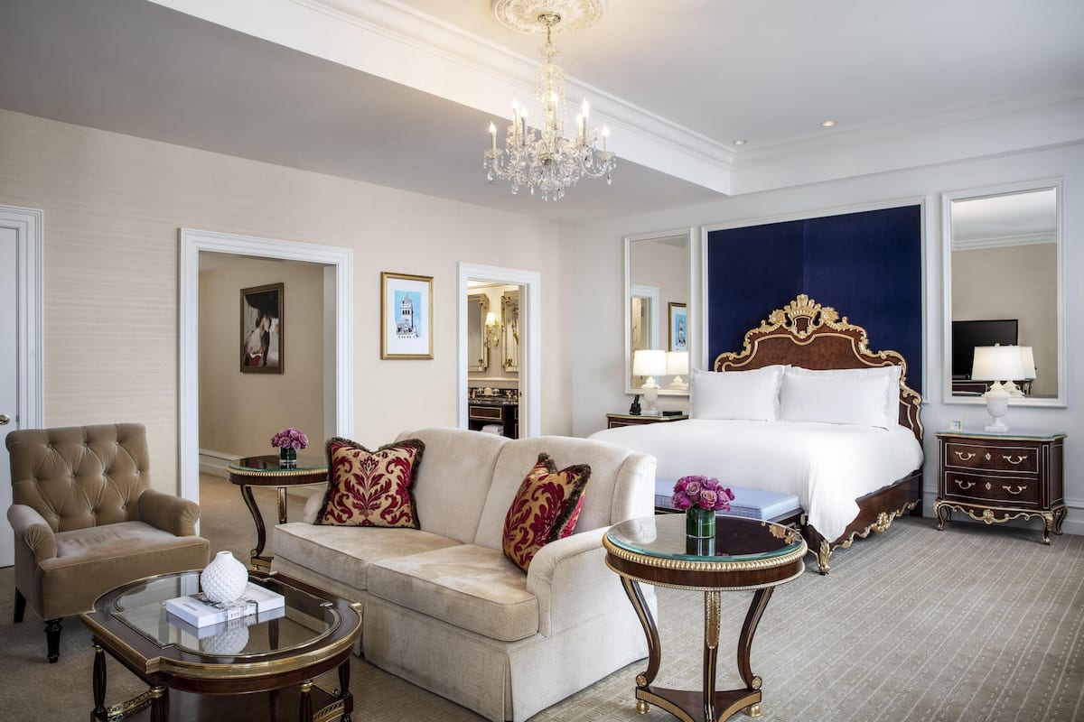 Ein Hotelzimmer mit einem großen Bett, einem Schlafsofa, einem Sessel, einem Couchtisch und einem Schminktisch.