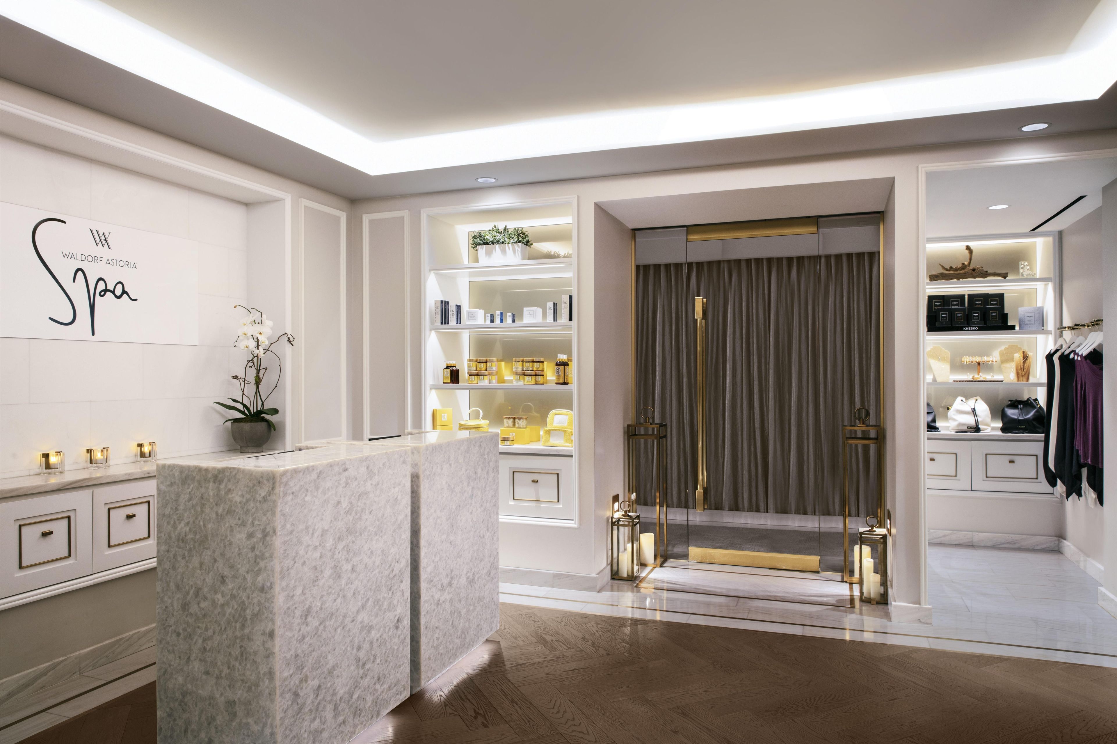 Een moderne spa met een receptiebalie, planken met verzorgingsproducten en een afgescheiden kleedruimte.