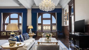 A spacious living room with a large chandelier, a sofa set, a coffee table, and a television.
