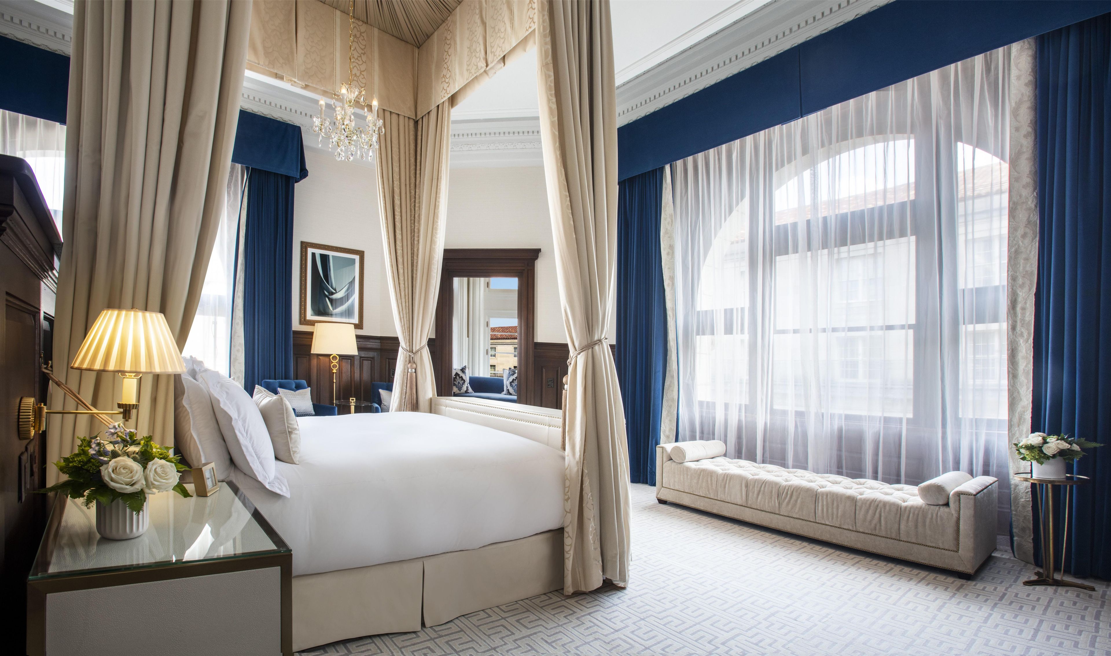 A spacious bedroom with a large bed, a sitting area, and a view of the city.