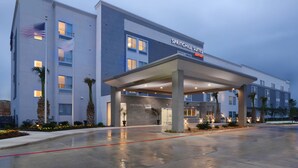 Un hotel moderno con un acceso cubierto, ventanas amplias y una fachada bien iluminada.