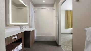 A modern bathroom with a large mirror, a bathtub, and a shower area.