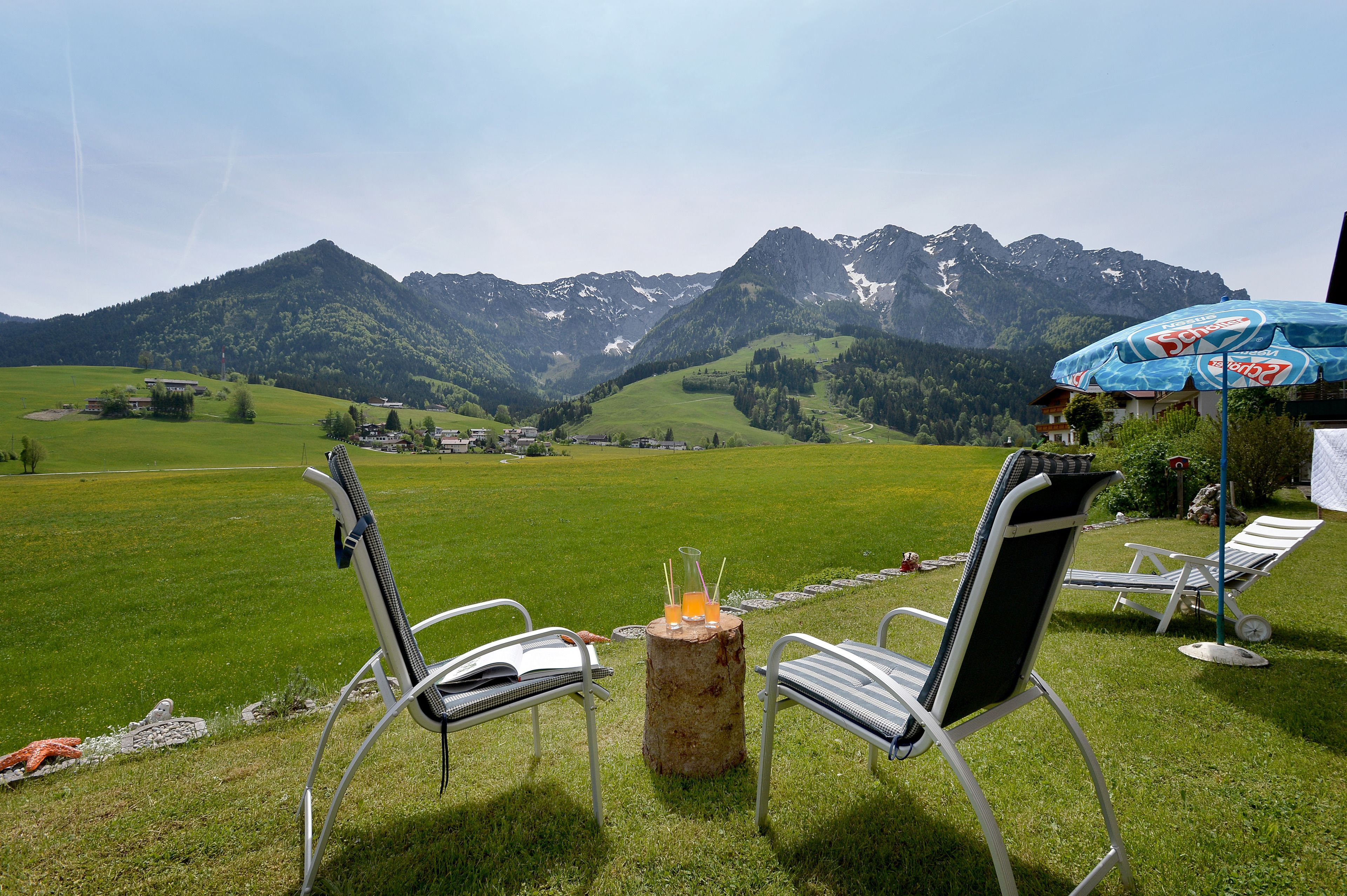 Ein schöner Außenbereich mit Sitzgelegenheit für zwei Personen und einem Tisch, mit Blick auf eine gebirgige Landschaft.