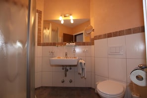 A bathroom with a sink, mirror, and toilet. - Hotel Garni Tirol (Walchsee)