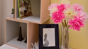 A corner shelf with a magazine, a vase with flowers, and a framed picture. - STSP Guest House (Tainan)