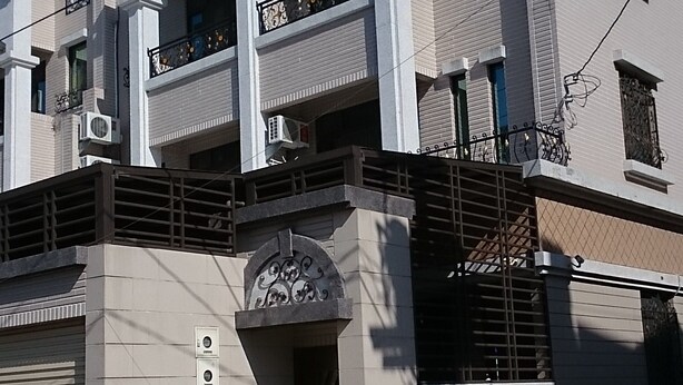 A multi-story building with balconies, a gated entrance, and a small door with a decorative arch. - STSP Guest House (Tainan)