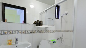 A bathroom with a white sink, toilet, and shower. There is a mirror above the sink and a window above the toilet. - STSP Guest House (Tainan)