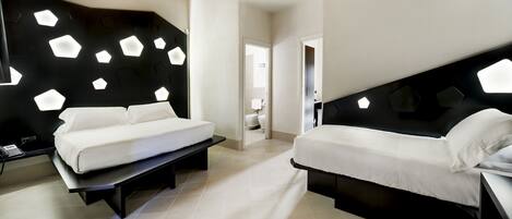 A modern hotel room with two beds, a desk, and a bathroom visible through an open door.