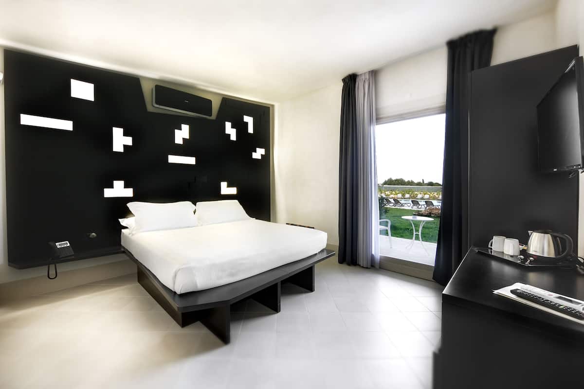 Ein modernes Hotelzimmer mit Bett, Schreibtisch, Flachbildfernseher und Blick auf einen Pool.