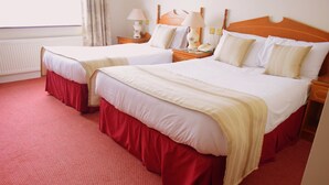 Une chambre d’hôtel avec deux lits, une moquette rouge, des têtes de lit en bois et des lampes de chevet.
