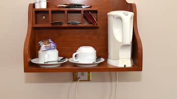 Eine wandmontierte Kaffeestation mit Kaffeemaschine, zwei Tassen und einem kleinen Ablagefach für Zutaten.