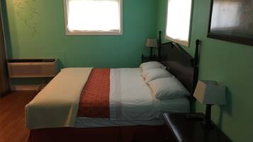 A room with a bed, a window, a nightstand, and a wall-mounted air conditioner.