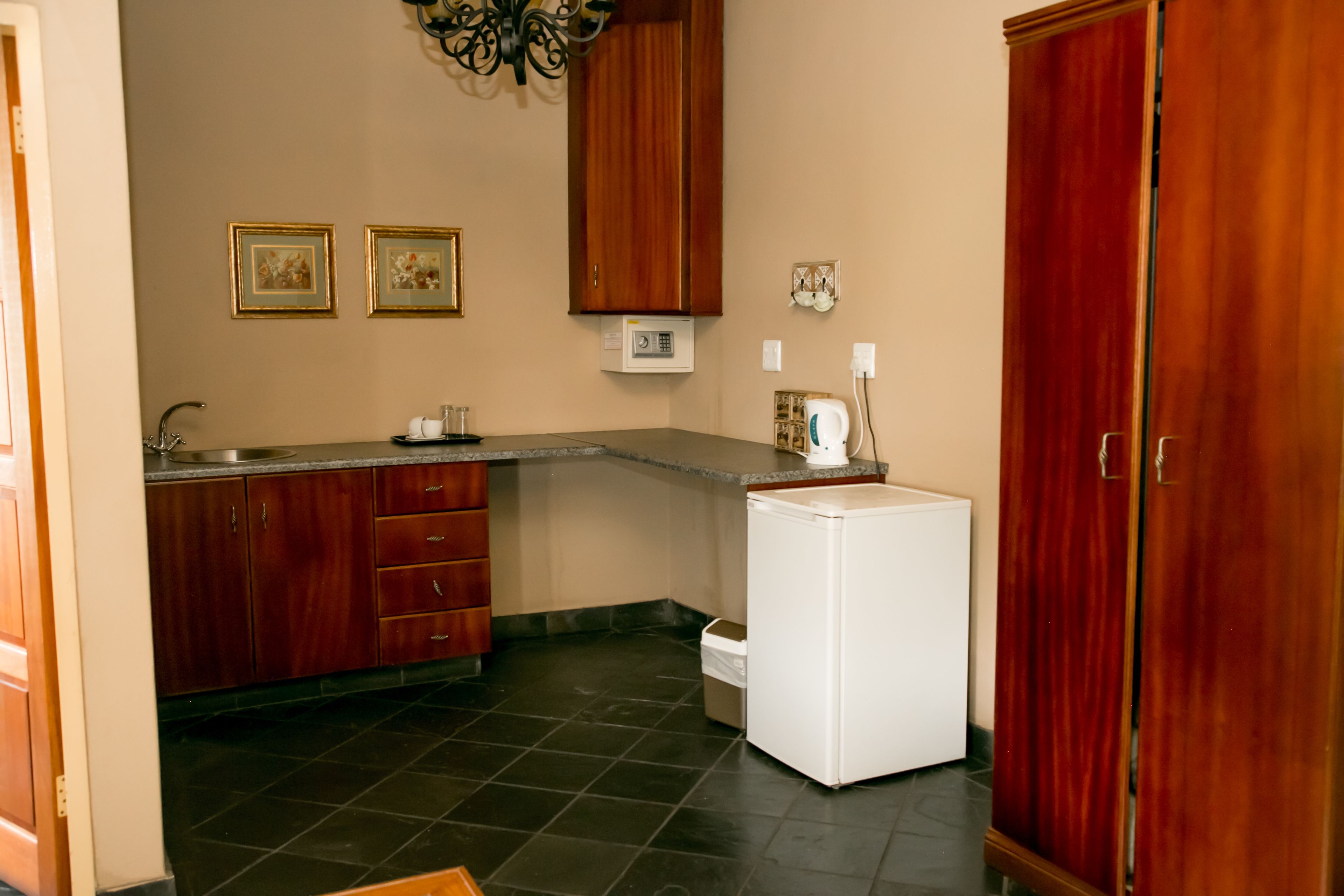 A kitchen with dark tiled flooring, wooden cabinets, a white refrigerator, and a microwave.