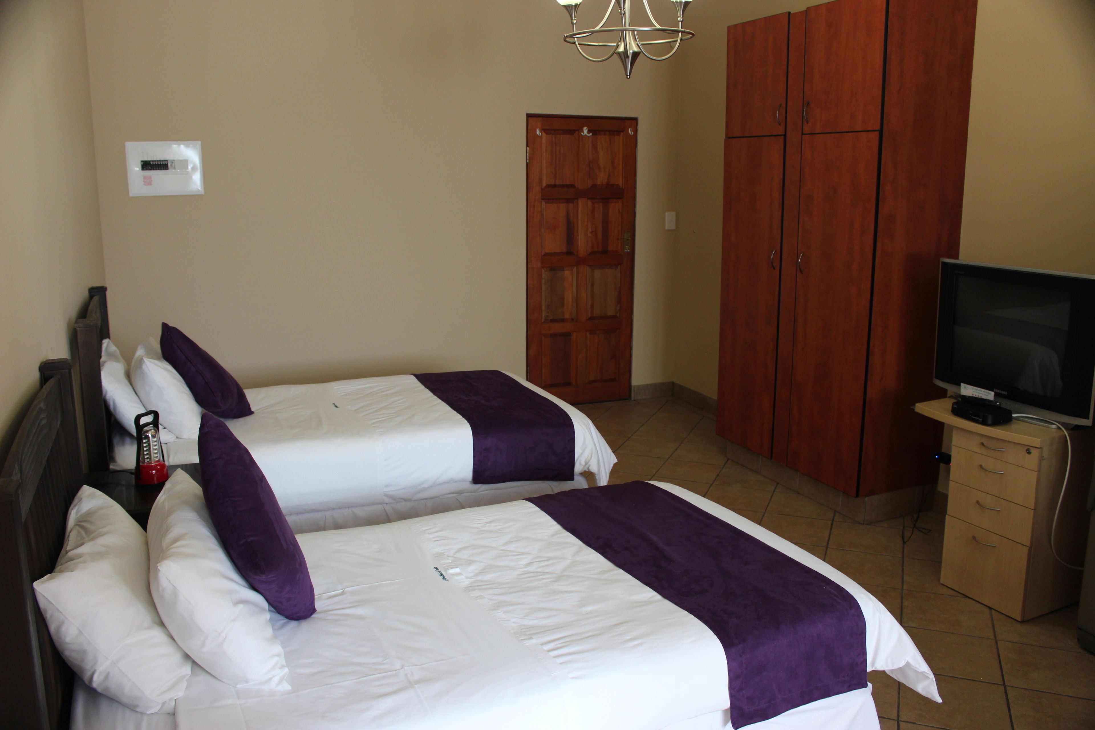Habitación de hotel con dos camas, un televisor, un armario y una puerta.