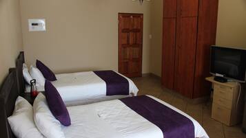 Habitación de hotel con dos camas, un televisor, un armario y una puerta.