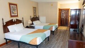 Quarto de hotel com duas camas, um aparador de madeira e uma porta que dá para outro cômodo.