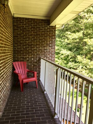A brick balcony with a red chair and a white railing. - Cumberland Gap Inn (Cumberland Gap)