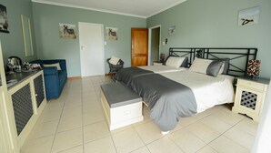 Une chambre à coucher comprenant un lit, des tables de chevet, un banc, une armoire et un bureau avec une chaise.