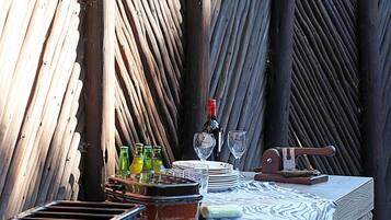 An outdoor dining area with a stone table, a woven fence, and a bottle of wine.