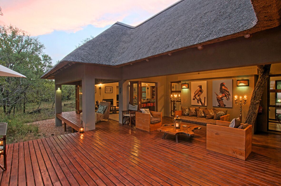 A wooden deck with outdoor seating and a thatched roof structure.