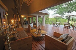A spacious outdoor seating area with wooden furniture and a thatched roof.